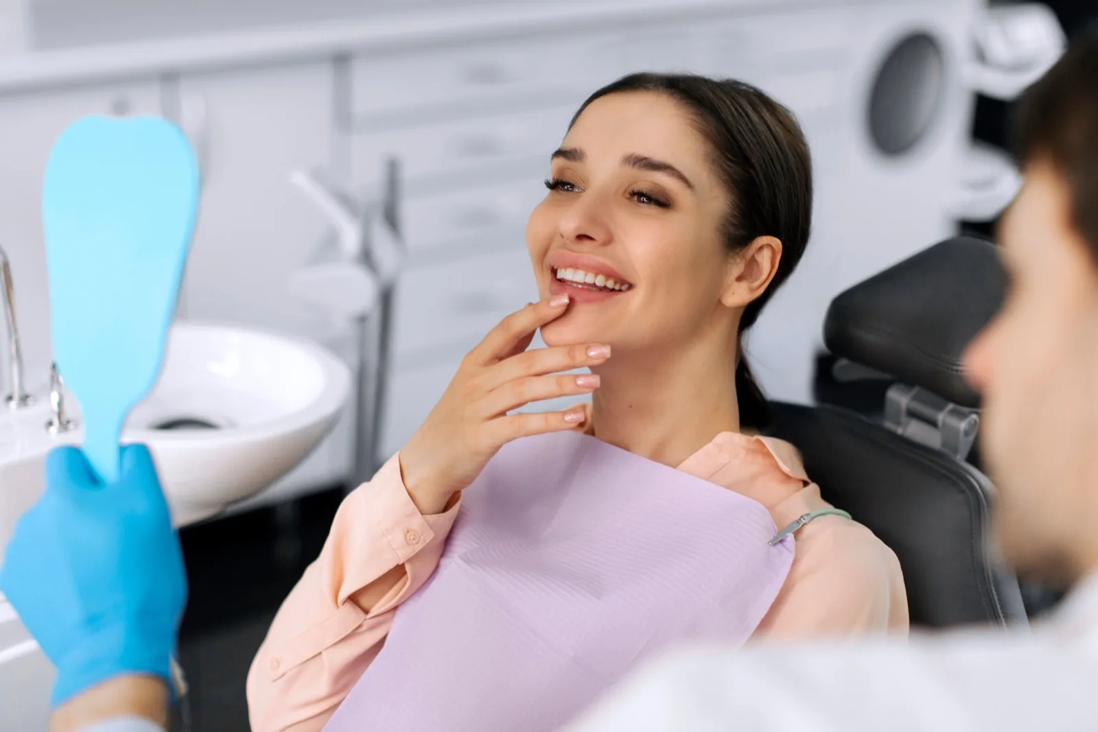 A patient admiring her new same-day crown in the chair at Isom Dentistry