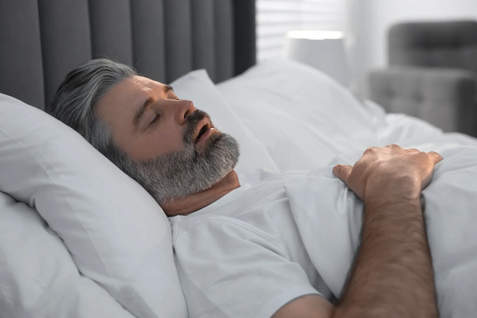 A man sleeping with his mouth open, a common sign of snoring and sleep apnea
